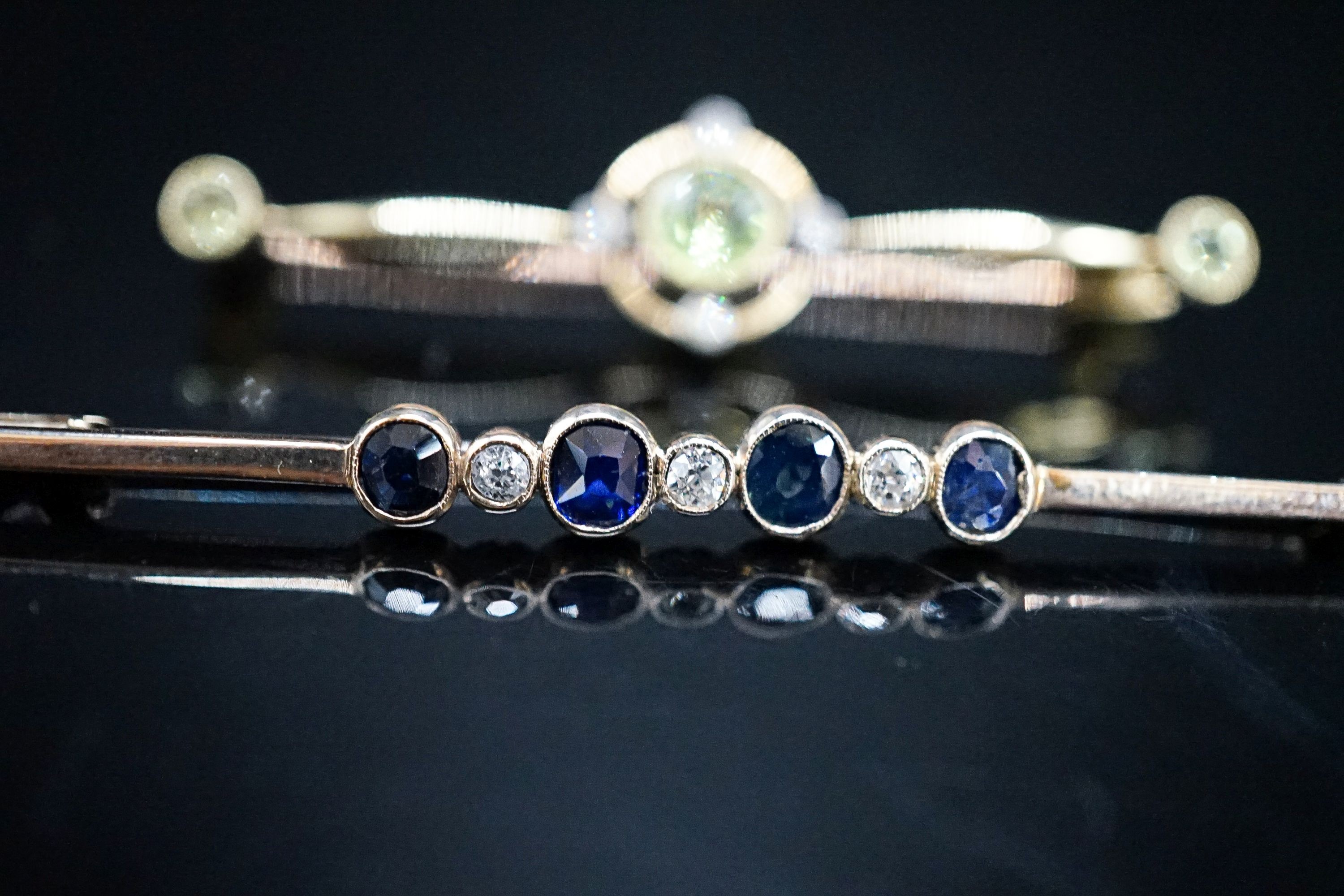 An Edwardian 15ct, peridot and diamond set bar brooch, 49mm, gross weight 4.4 grams and a yellow metal, sapphire and diamond set seven stone bar brooch, gross 3 grams